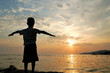 The silhouette of child against the sunset at sea