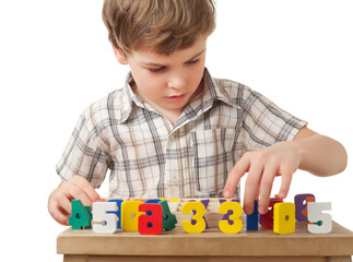 boy in shirt displays wooden figures in form of numerals