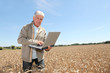 © goodluz - Agronomist in wheat field with laptop computer