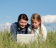 © Yevgeniy Zateychuk - Two girls playing laptop on grass