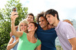 © goodluz - Group of friends taking picture with mobile phone