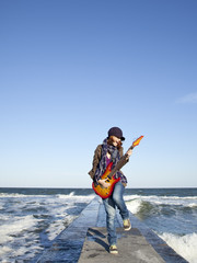 Poster - Young red-haired girl play on guitar at windy day.