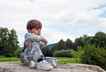 A little boy sitting on a felled tree