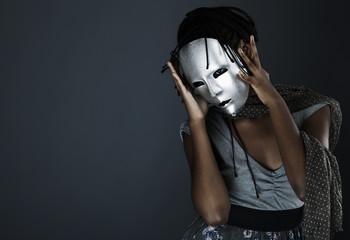 gloomy woman in silver mask posing on a black background.