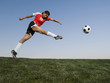 © Erik Isakson/Blend Images - Mixed race woman kicking soccer ball