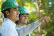 © Karin Dreyer/Blend Images - Hispanic businessmen in green hard hats pointing outdoors