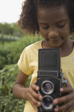 African Girl Holding Retro Camera In Garden