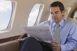 © REB Images/Blend Images - Hispanic businessman reading newspaper on airplane