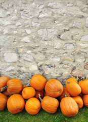 pumpkins piled against a rustic stone wall