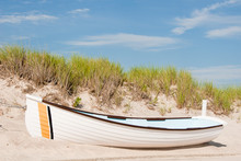 White Lifeguard Boat On The Sand In Front Of A Sand Dune