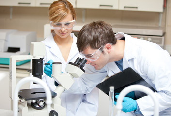 Two scientists observing something with a microscope