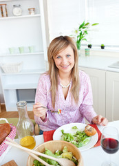 Wall Mural - Beautiful woman eating salad in the kitchen