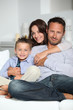 © goodluz - Closeup of parents and child relaxing at home on sofa