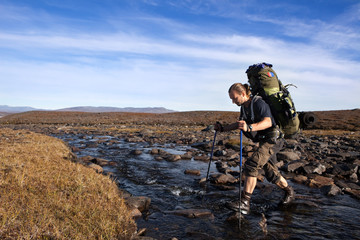 Wall Mural - hiker is crossing the river