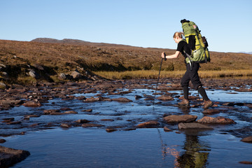 Wall Mural - female hiker is crossing the river