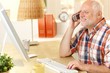 © nyul - Senior man talking on cellphone, using computer