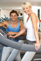 Senior Woman Working With Personal Trainer On Running Machine In