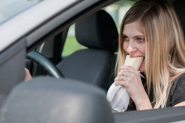 Wall Mural - Portrait of young woman eating while driving car