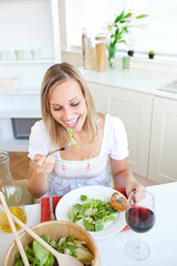 Wall Mural - Portrait of a beautiful woman eating a salad in the kitchen