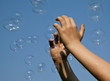 © Alta Oosthuizen - Hands catching bubbles against a blue sky in sunshine
