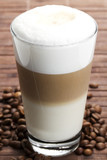 latte macchiato mit kaffeebohnen auf hölzernem hintergrund
