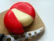 Red ball of cheese on wooden board with knife