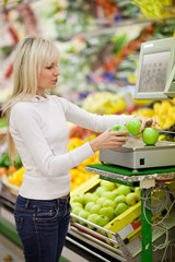 Beautiful young woman shopping for fruits and vegetables in prod