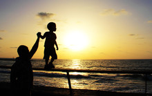 Silhouettes Of Father And Son On Sunset Sea Background