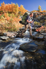 Wall Mural - wanderer beim queren eines baches im herbst