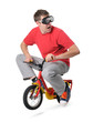 © afxhome - Male in goggles jump on a children's bicycle, withe background