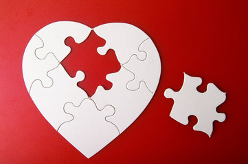 white puzzle heart shape with missing piece, on red