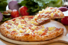 Whole Hawaiian Pineapple And Ham Pizza, On Wooden Board With Ingredients, Lifted Slice