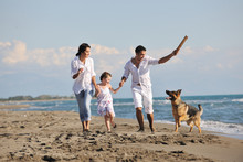 Happy Family Playing With Dog On Beach