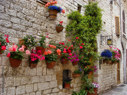 Nowoczesny obraz na płótnie Colorful flowers lining a medieval stone wall in Italy