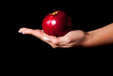 Fototapeta  - Woman holding red apple on black background