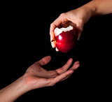 Fototapeta  - Woman hand giving an apple to man on black background
