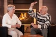 © nyul - Retired couple playing cards in front of fireplace