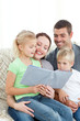 © WavebreakMediaMicro - Adorable family reading a book together in the living-room
