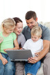 © WavebreakMediaMicro - Adorable family working together on a laptop sitting on the sofa