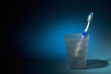 Fototapeta Dmuchawce - Tooth brush in matte plastic glass over dark blue background.