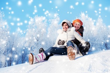 Mother and daughter sliding in the snow