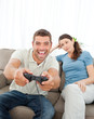 © WavebreakMediaMicro - Bored woman looking at her boyfriend playing video game on the s