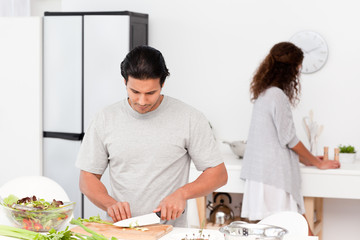 Wall Mural - Hispanic couple preparing a salad together in the kitchen