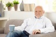 © nyul - Smiling elderly man having coffee on sofa