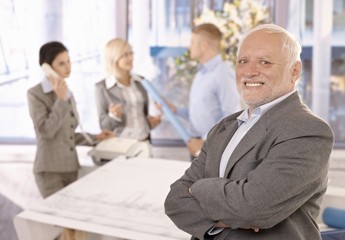 Wall Mural - Proud smiling senior businessman with team