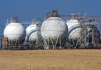 white rounded oil tanks and agriculture field