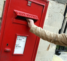 Posting A Letter Into A Traditional Red English Postbox