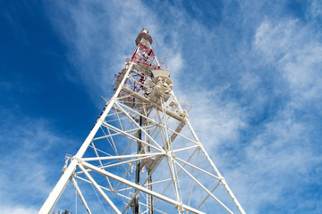 Telecommunication tower with antennas against blue sky backgroun