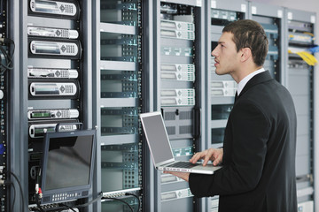 businessman with laptop in network server room