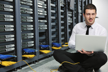 businessman with laptop in network server room